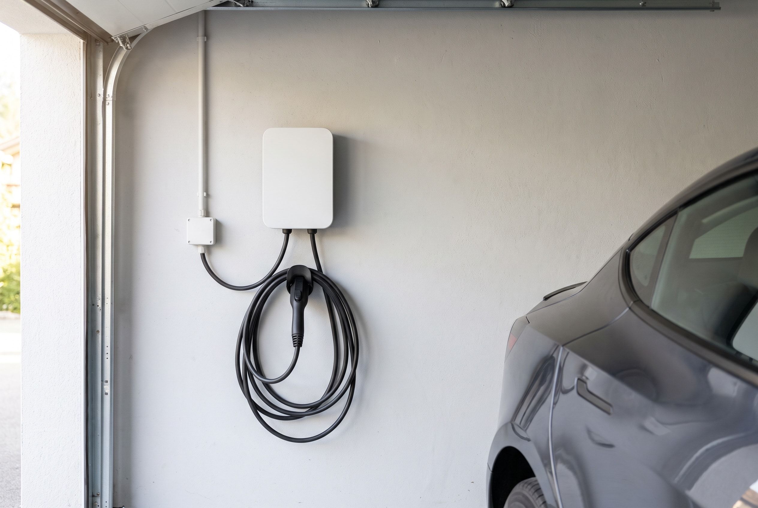 Weisse Ladestation für ein Elektroauto an der Wand einer Garage